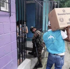Military accompanied by GANA or Nuevas Ideas (logo on vest used to be Nuevas Ideas) party members deliver a box of goods to Salvadoran families in violation of campaign laws.